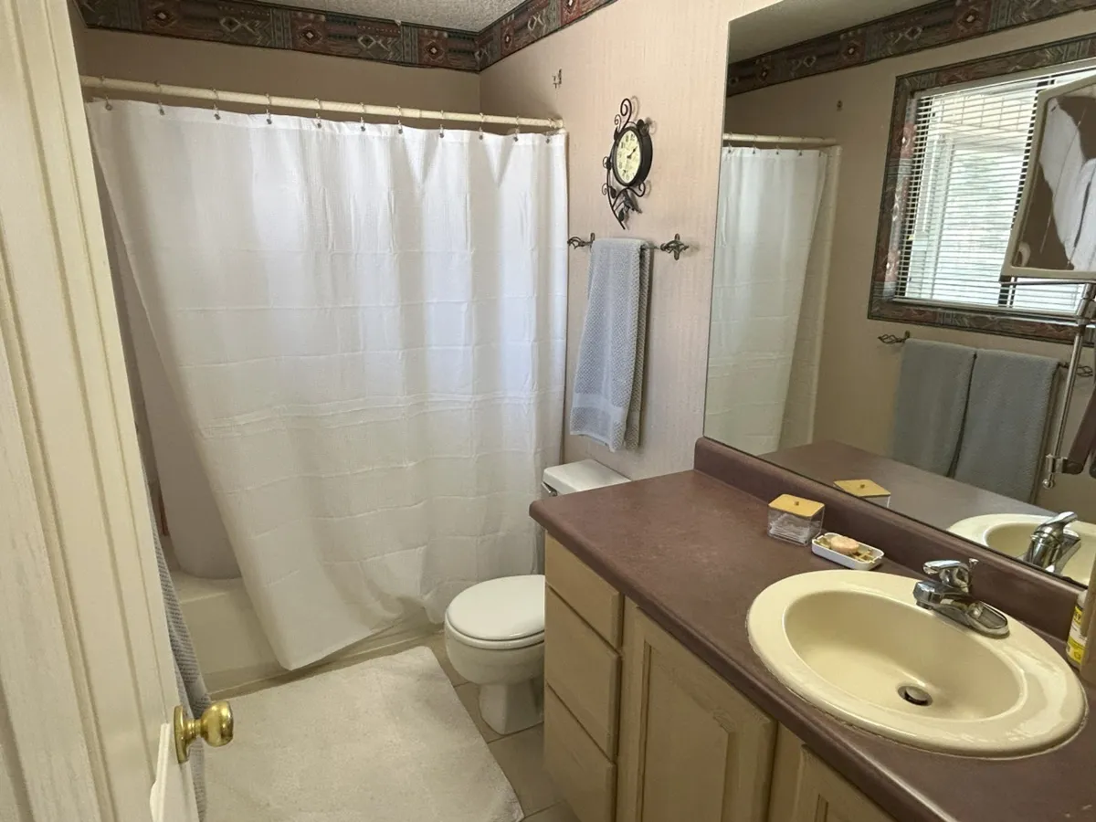 A calm, organized bathroom scene featuring a mirror, shower curtain, and a neatly arranged sink area. The space feels fresh and functional, offering a tranquil spot to refresh after a day outdoors.