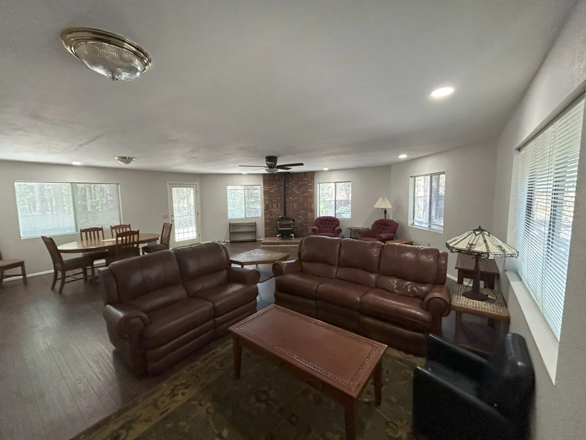 Featuring a wooden dining table adjacent to leather sofas and a brick accent wall, this interior shot sets a cozy and inviting atmosphere. The dining table is clearly a focal point for social gatherings, meals, and shared activities, seamlessly blending with the living area for a communal feel.